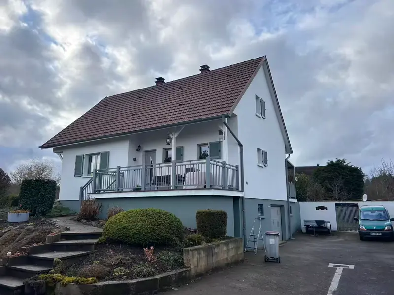 Après : la même maison, façade repeinte en blanc et soubassement gris