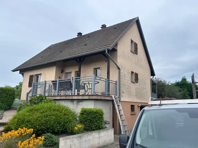 Avant : maison à balcon, façade beige ternie et soubassement brun