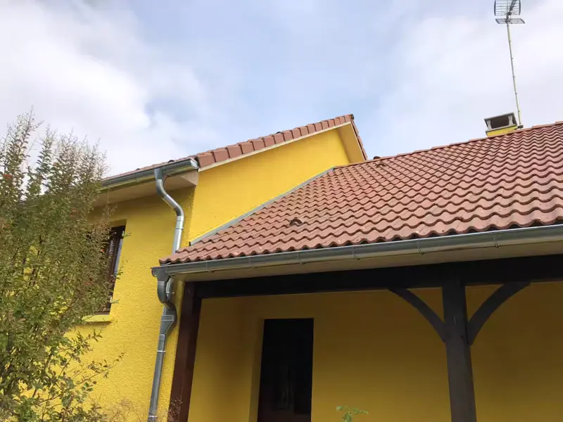 Après : la même maison, façade repeinte en jaune et toiture nettoyée